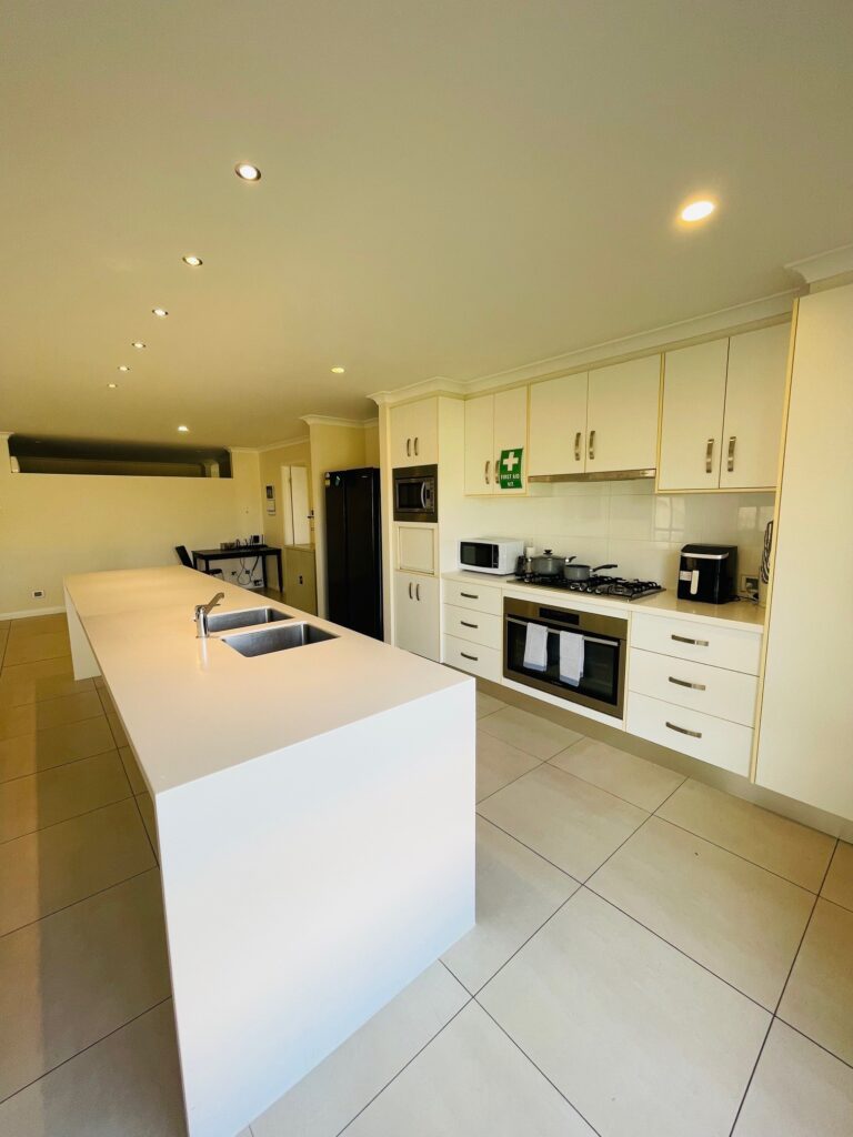 Community Living Association Baltic Ridge view of open plan kitchen, with oven, microwave, island bench with two sinks.
